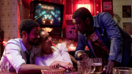 Film still from Executive Order (2020). Image of three people at a bar, talking.